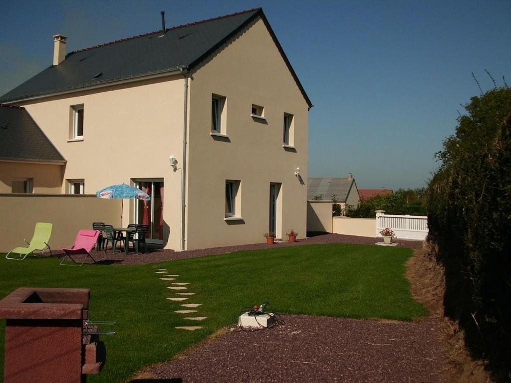Cette grande maison blanche dispose d'une cour avec une terrasse. dans l'établissement Les Pieux -6km de la mer, à Grosville