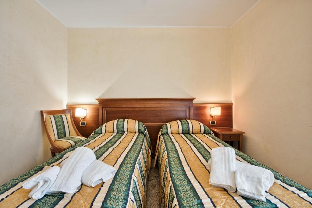 due letti in una stanza d'albergo con asciugamani sopra di Hotel Flora a Lignano Sabbiadoro