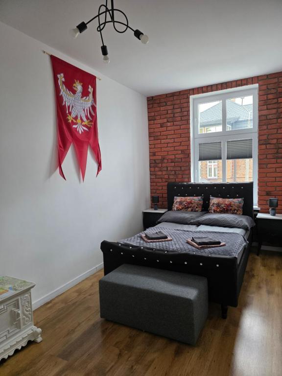 a bedroom with a bed and a flag on the wall at Apartamenty Zakonne "Apartament Wielkiego Mistrza" in Malbork