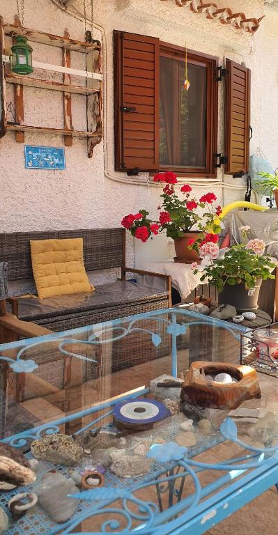 a glass table in front of a house with flowers at Peace&love-sea studio in Poros