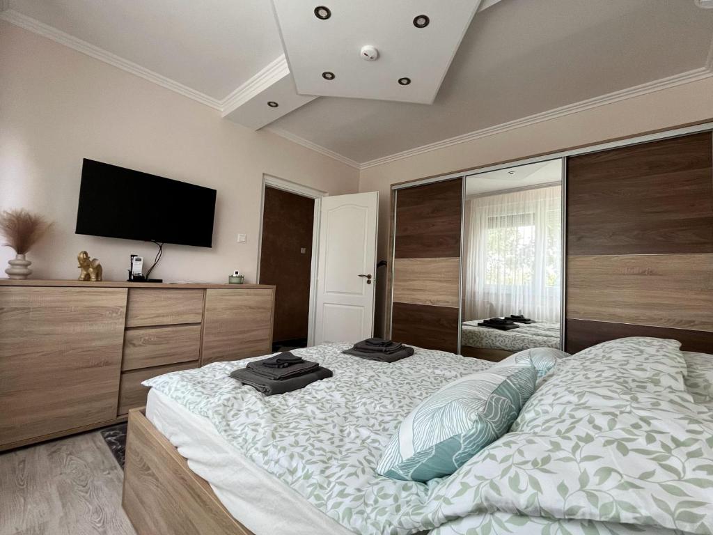 a bedroom with a large bed and a flat screen tv at Maros Apartman in Makó