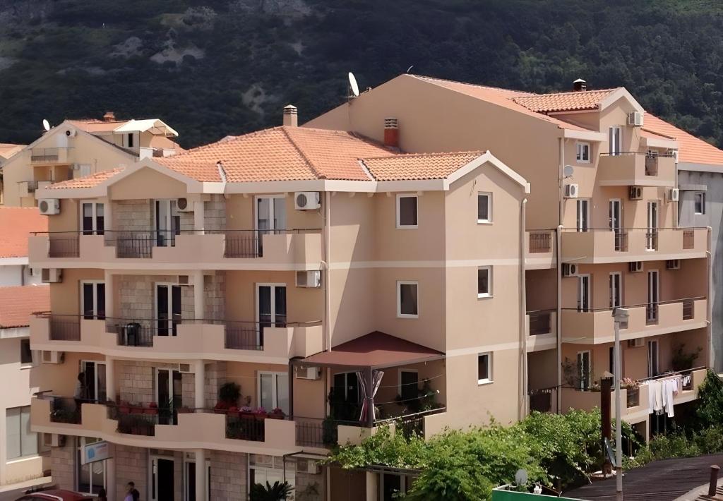 Un gran edificio de apartamentos con una montaña al fondo. en Apartmani Goran i Jelena Zec, en Budva