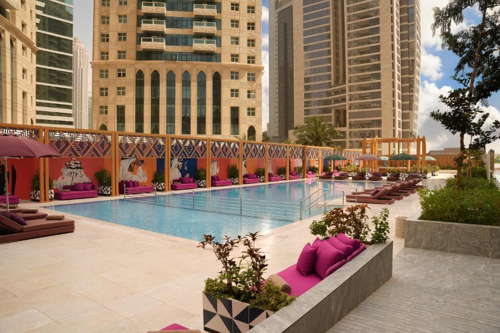 duży basen z różowymi poduszkami obok budynków w obiekcie Andaz Doha, by Hyatt w mieście Doha