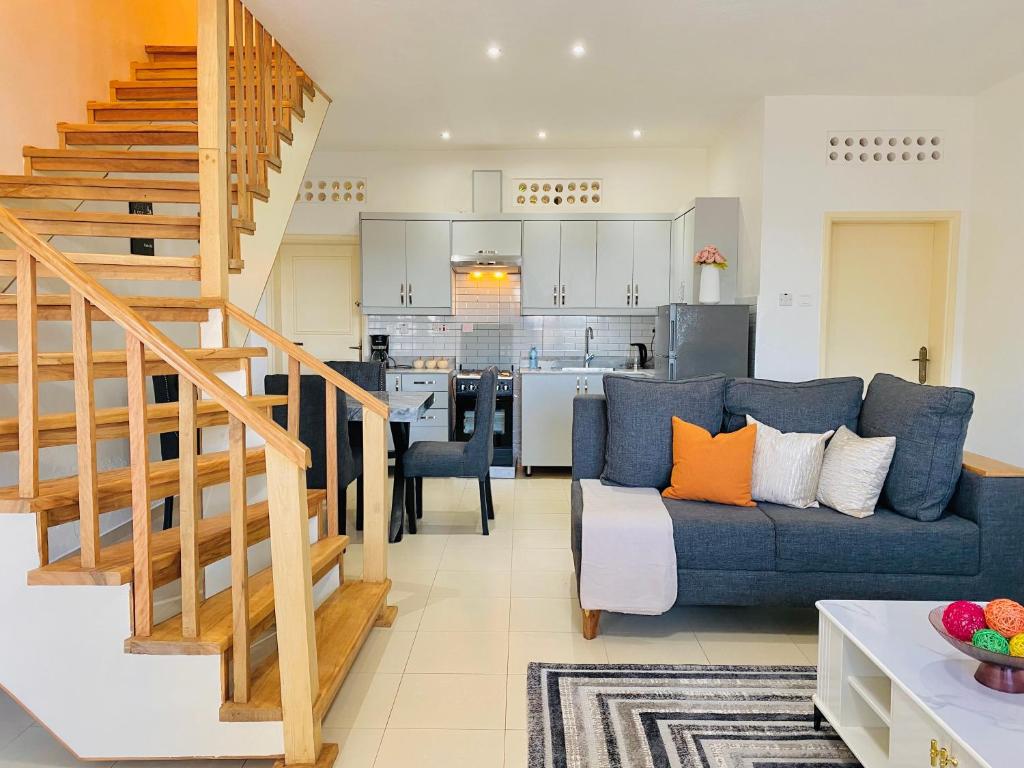 a living room with a blue couch and a kitchen at SHALOM HOMEs in Kampala