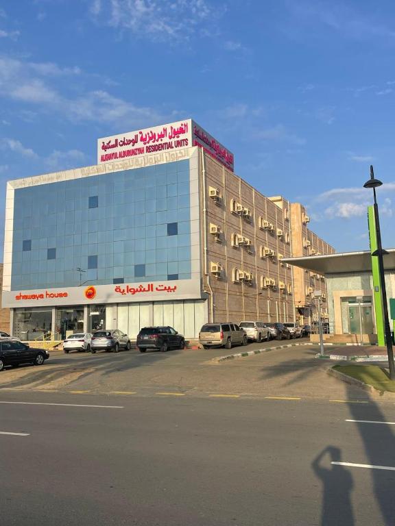 a large building with cars parked in a parking lot at شقق الخيول البرونزية للشقق المخدومة in Şabyā