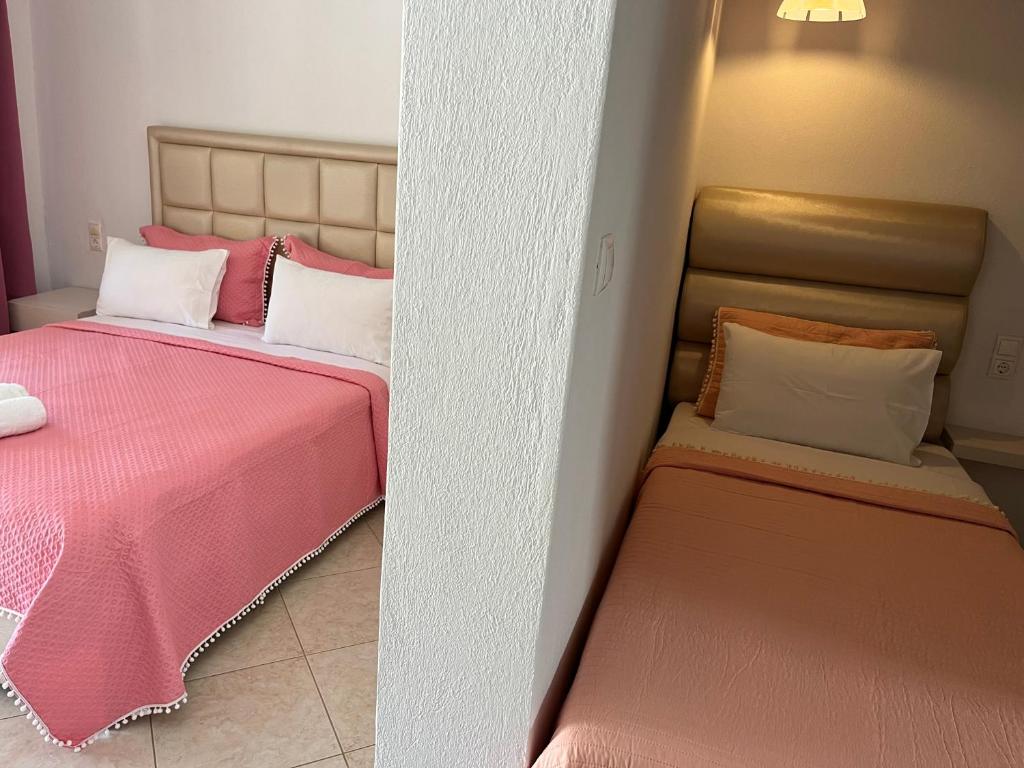 two beds in a room with pink and white pillows at Maniatis Garden in Achladies