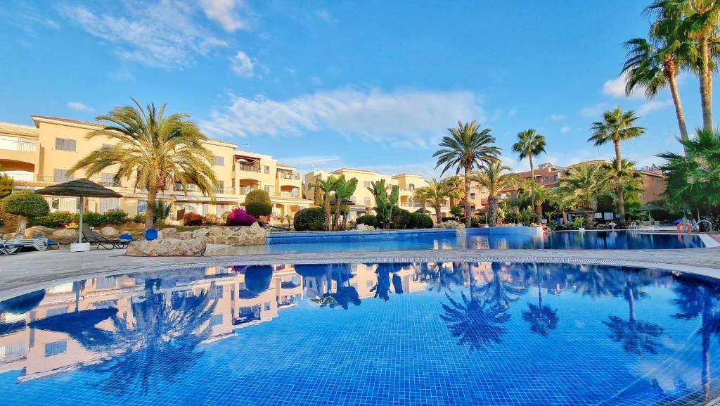 a large swimming pool with palm trees and buildings at CSS Cheerful Smart Superior 2BD Townhouse Limnaria Gardens in Paphos City