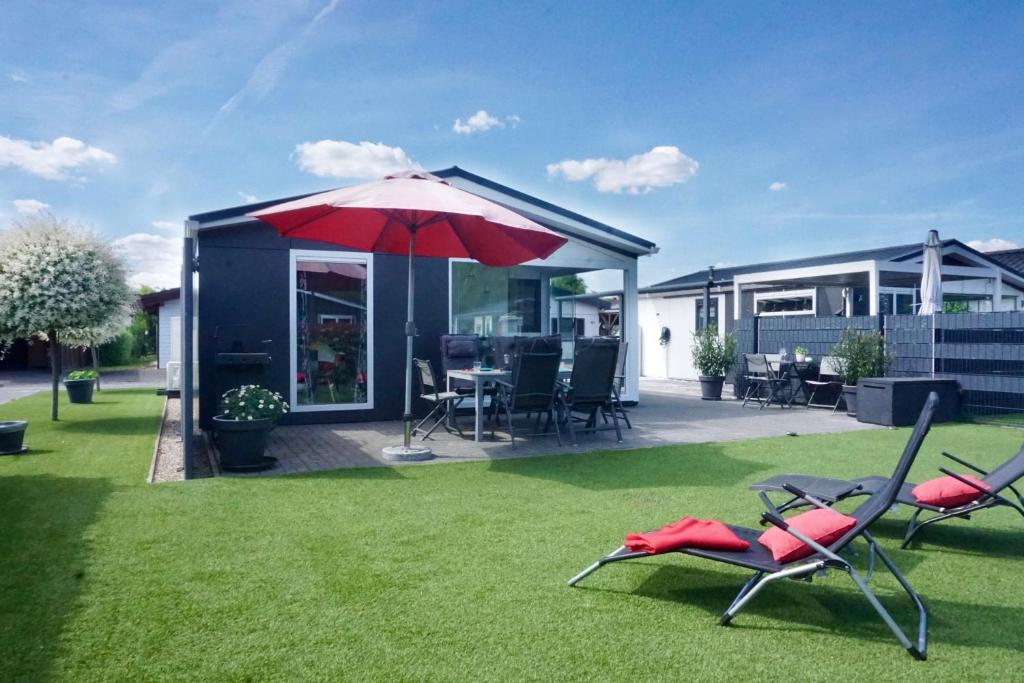 a house with a lawn with two chairs and an umbrella at Ferienhaus Ufergeheimnis am Gülser Moselbogen I 2 SZ I 5 Gäste I Badebucht I Grill I Garten in Koblenz
