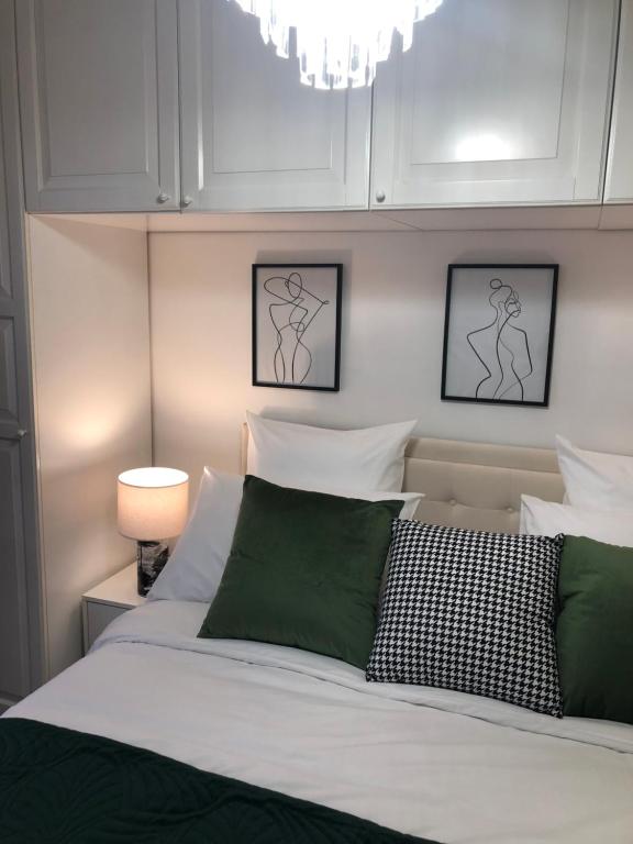 - une chambre avec un lit doté d'oreillers verts et blancs dans l'établissement Le confort et l'élégance à deux pas de Paris, à Cachan