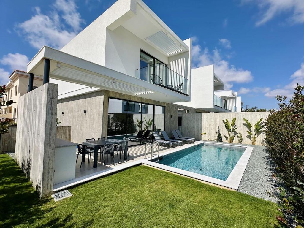 a villa with a swimming pool in front of a house at Elysian Blue villa 4 in Paphos City