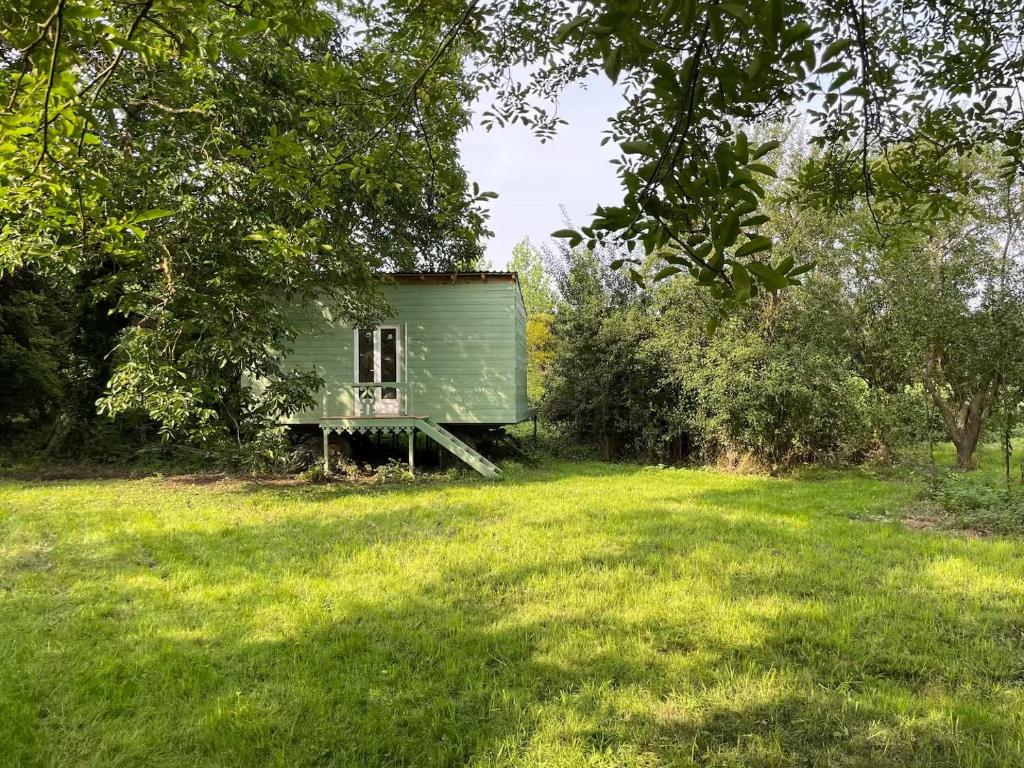 ein grüner Schuppen mitten auf einem Feld in der Unterkunft Le cottage du Manoir 1900 in La Ferté-Gaucher