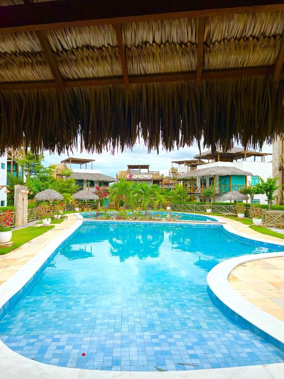 a large swimming pool in a resort with an umbrella at Chaleville Barrinha in Barrinha