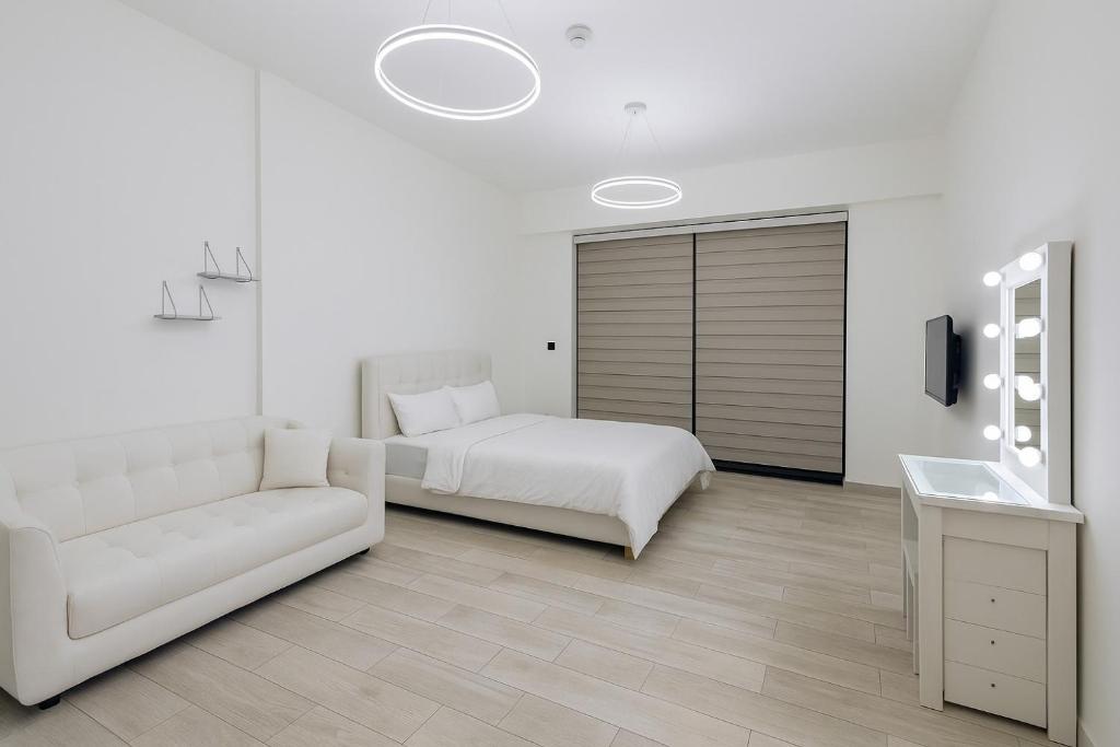 ein weißes Schlafzimmer mit einem Bett und einer Couch in der Unterkunft Nice Studio for rent at Jumeirah Village Circle Dubai in Sabkhah