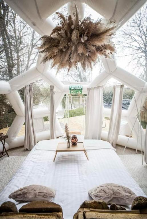 une chambre avec un grand lit blanc avec un lustre dans l'établissement Le Dôme, séjour sous les étoiles au bord du lac, à Prouilly