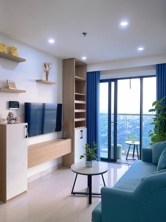 a living room with a blue couch and a tv at Joie Apartment Hue in Thôn Văn Dương