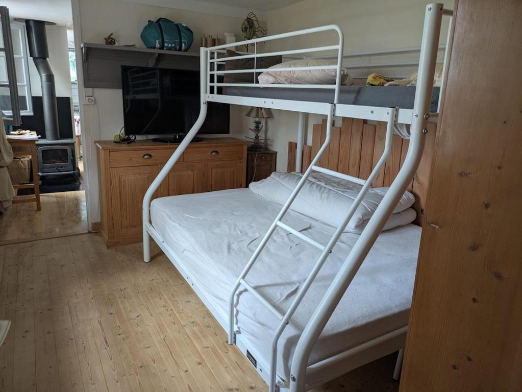 a bedroom with two bunk beds and a television at Pink Granite Coast Cottage between forest and sea in Trélévern