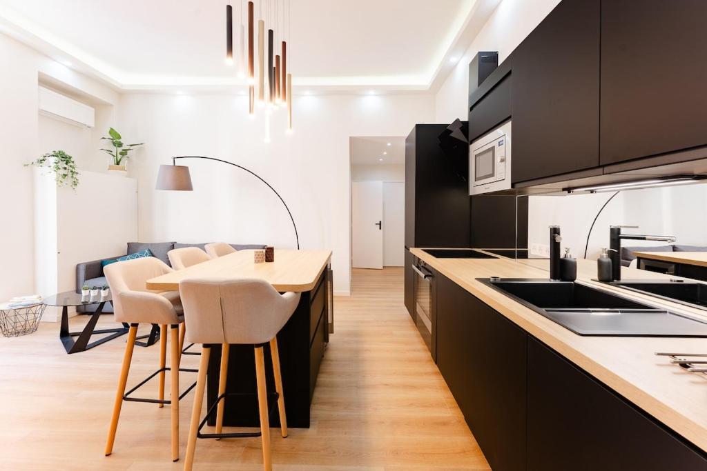 une cuisine avec des placards noirs et une table avec des tabourets dans l'établissement Ambiance cosy a la Niçoise, à Nice