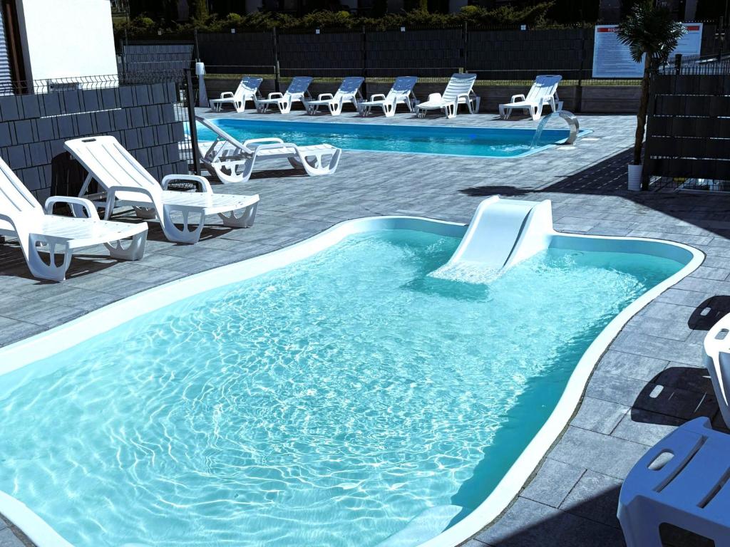 una piscina con sillas y un tobogán. en Ośrodek Wczasowy Amelia, en Jarosławiec
