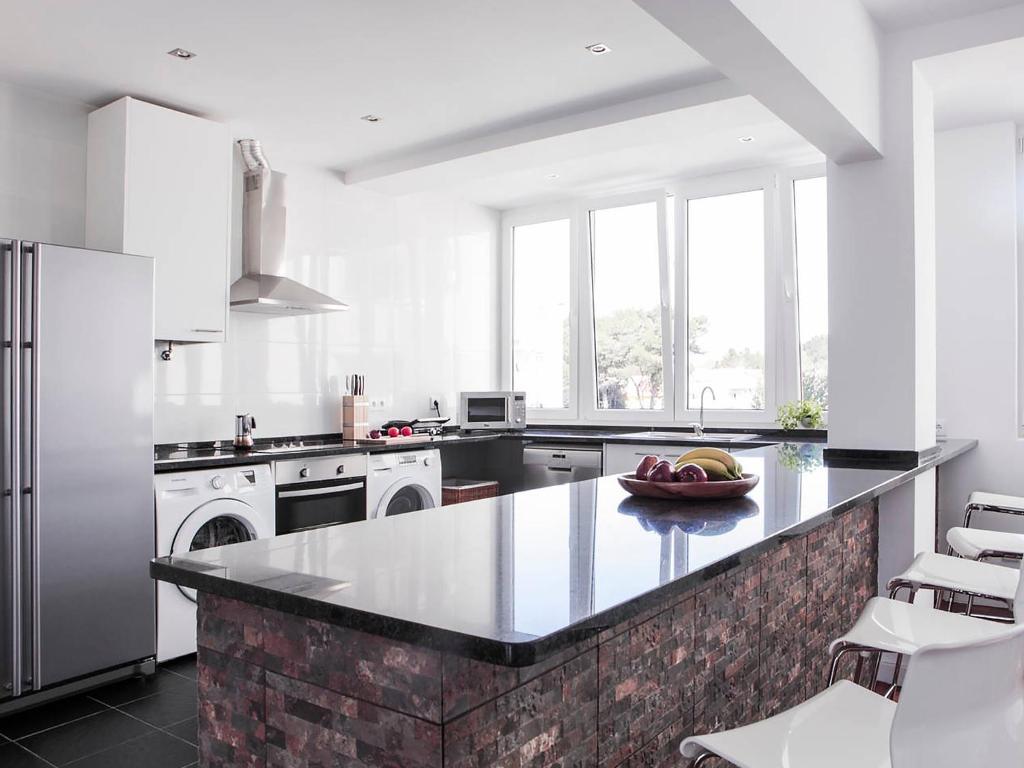 a kitchen with white appliances and a counter with a bowl of fruit at casaRene in Carcavelos