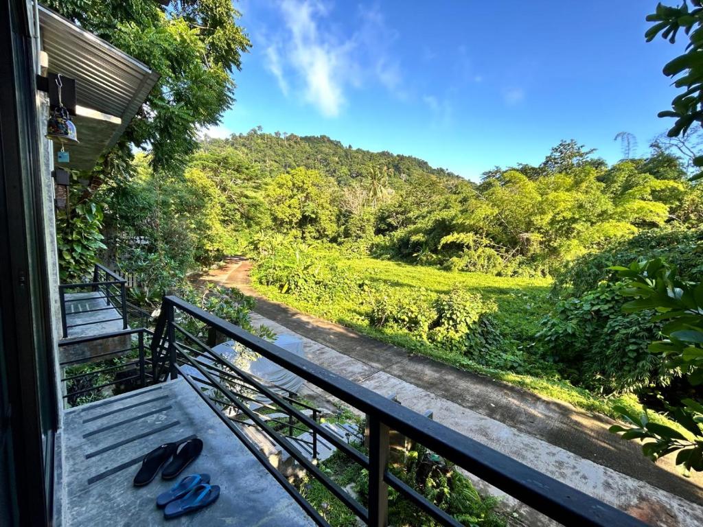 a balcony with a bench with a view of a forest at Phuchada Residence in Nai Yang Beach