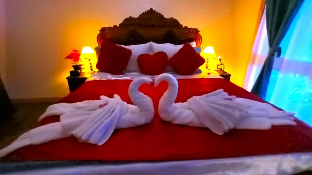 zwei Schwäne machen ein Herz auf einem Bett in der Unterkunft Chan Beach Resort & Hotel in Bahūr
