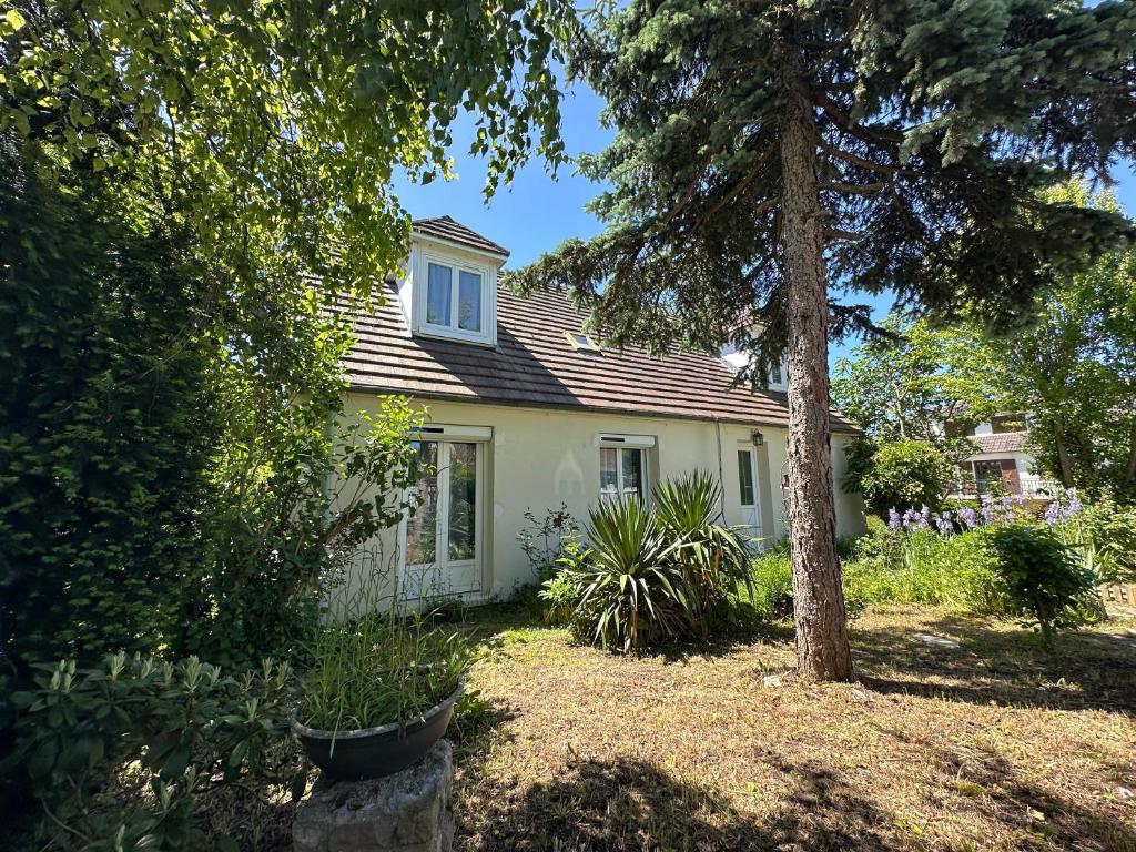 une maison blanche avec un arbre dans la cour dans l'établissement Family home close to Chantilly, Astérix, CDG, à Chaumontel