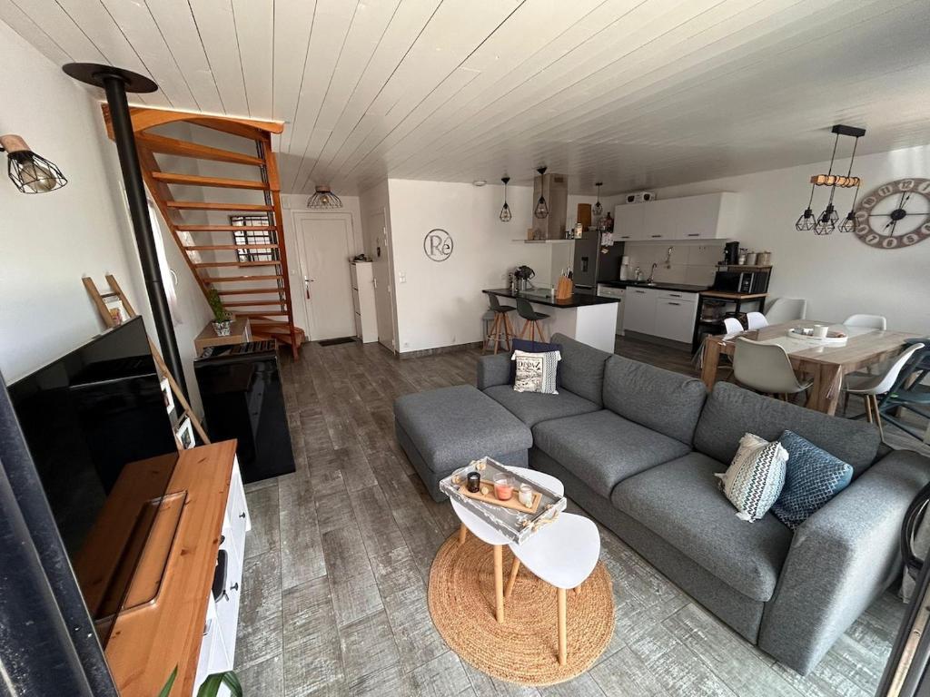 un soggiorno con divano grigio e una cucina di Charmante maison de Gros-Jonc a Le Bois-Plage-en-Ré