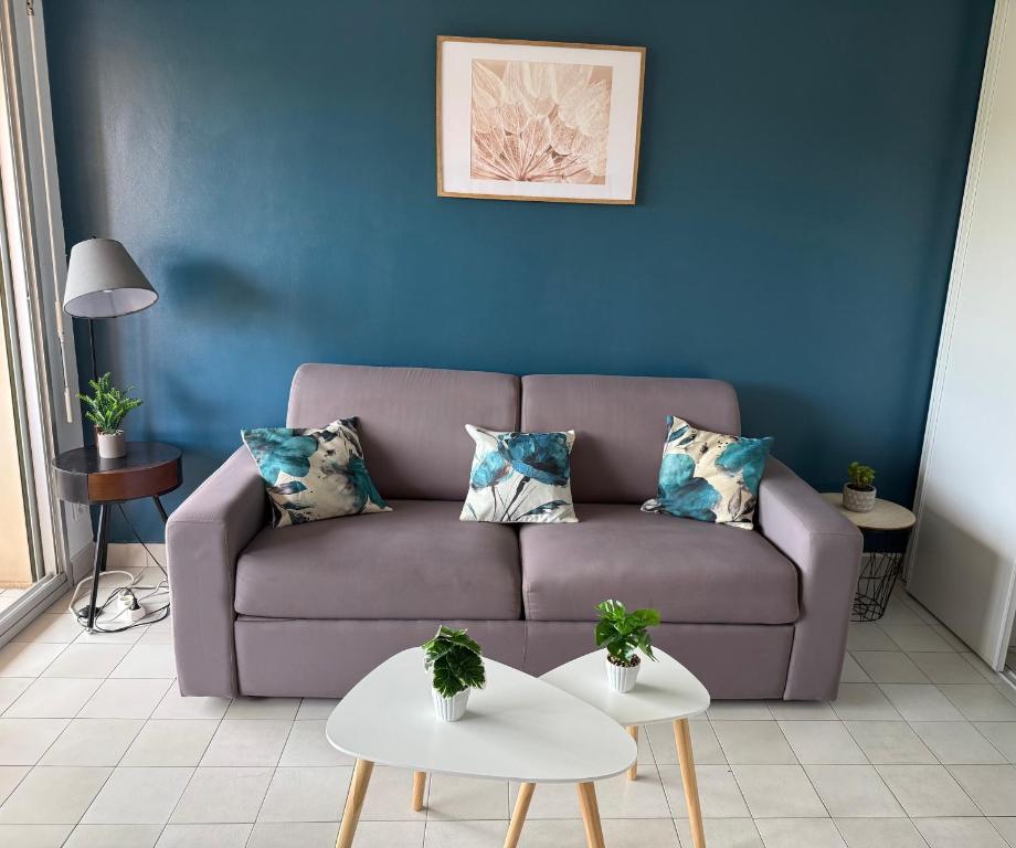 un salon avec un canapé et un mur bleu dans l'établissement Studio Fréjus Plage l Clim l WiFi l Parking privé, à Fréjus