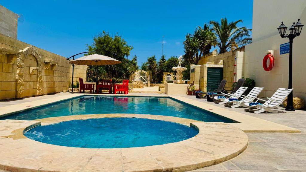a swimming pool with chairs and a table and an umbrella at See You Mystic Flowers & Private Pool in Għarb