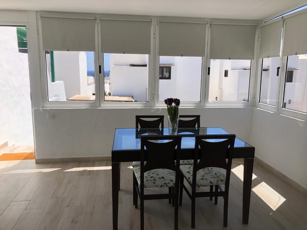 a dining room with a table and chairs and windows at Casa Yolanda in Tías