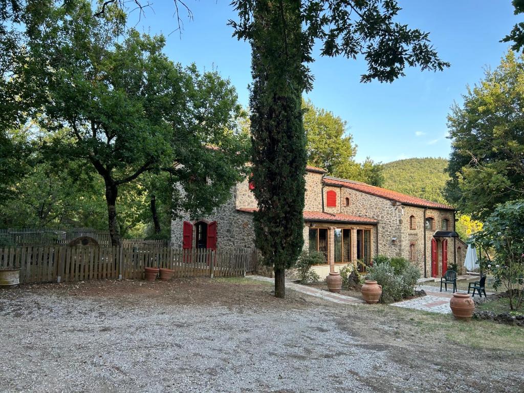 a stone house with a fence and a tree at Podere Diacciolini near Massa Marittima in Fontalcinaldo
