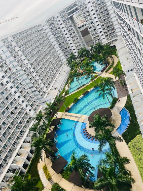 an overhead view of a large building with a pool and palm trees at Shell Residences MOA by Kirstie in Manila