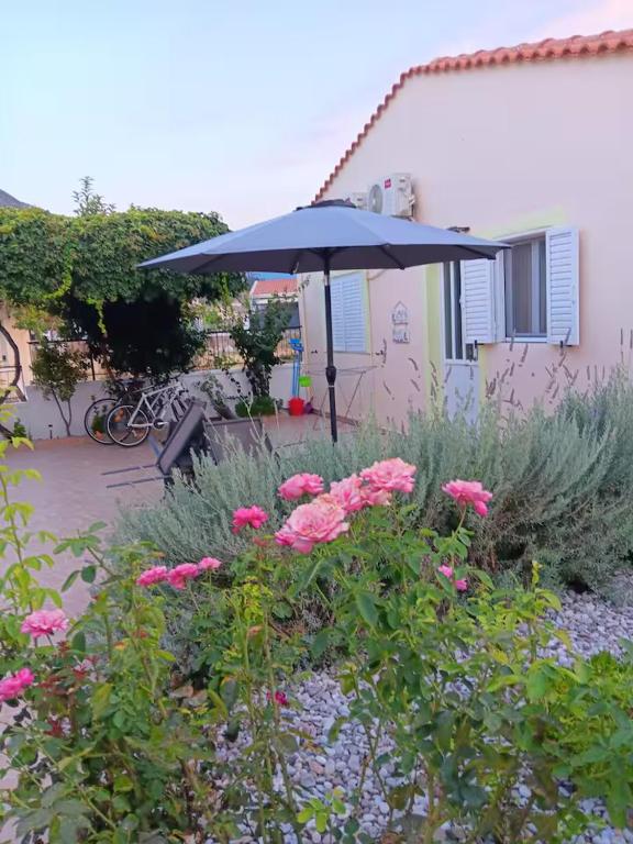 a blue umbrella in a garden with pink flowers at Tonia's guest house in Sami