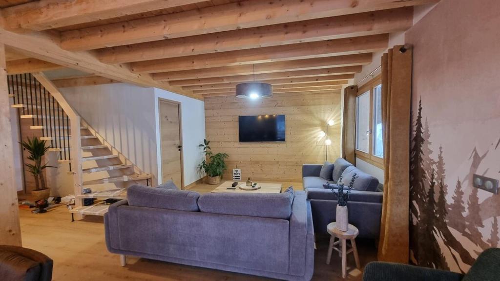 - un salon avec deux canapés bleus et un escalier dans l'établissement Chalet neuf Virage 12 , Tour de France 1st line, à La Plagne Tarentaise