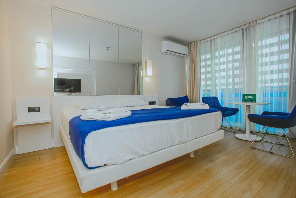a bedroom with a large bed and two blue chairs at Room number 2046 in Batumi