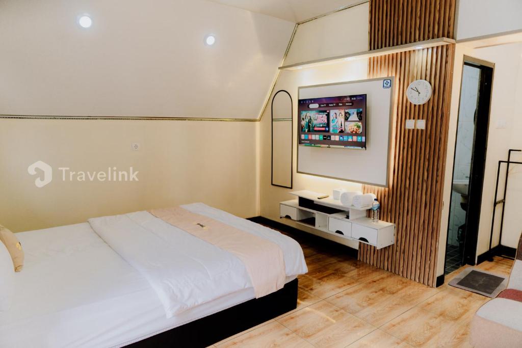a hotel room with a bed and a flat screen tv at Vianda Cabin By Travelink in Kejajar