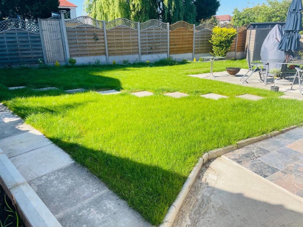 a yard with green grass and a fence at Tudor Close NW9 8SU in London