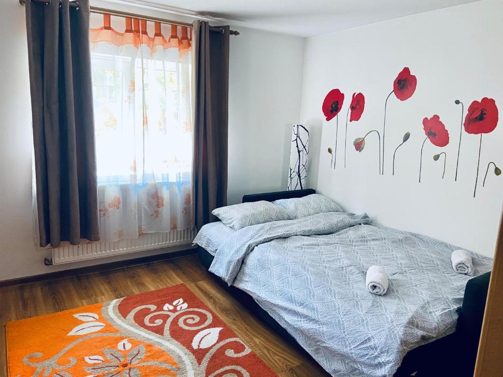 a bedroom with a bed and a window with red flowers on the wall at Closca Apartment 1 Max in Floreşti