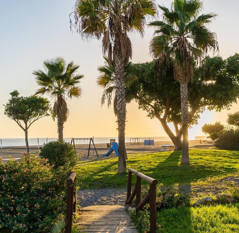a path leading to a beach with palm trees at Casa familiar con patio privado y piscina comunitaria cerca de la playa in Málaga