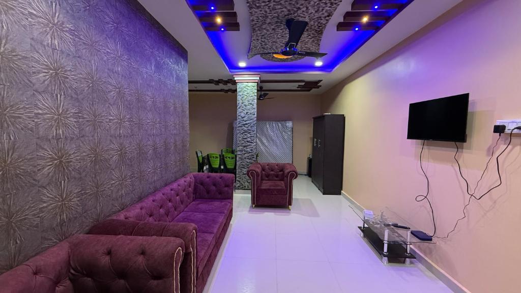 una sala de espera con sofás morados y TV en The Aurelia Inn, en Sibsāgar