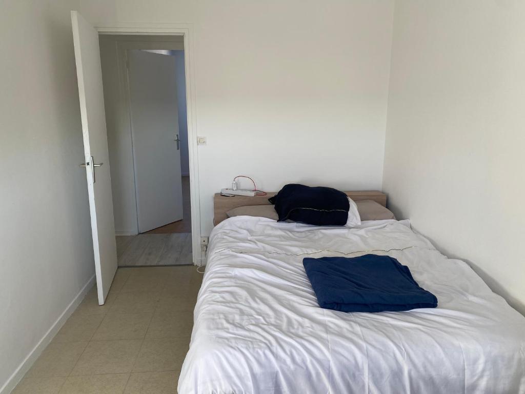 un lit dans une chambre blanche avec deux sacs dessus dans l'établissement Location 24h Le Mans, au Mans