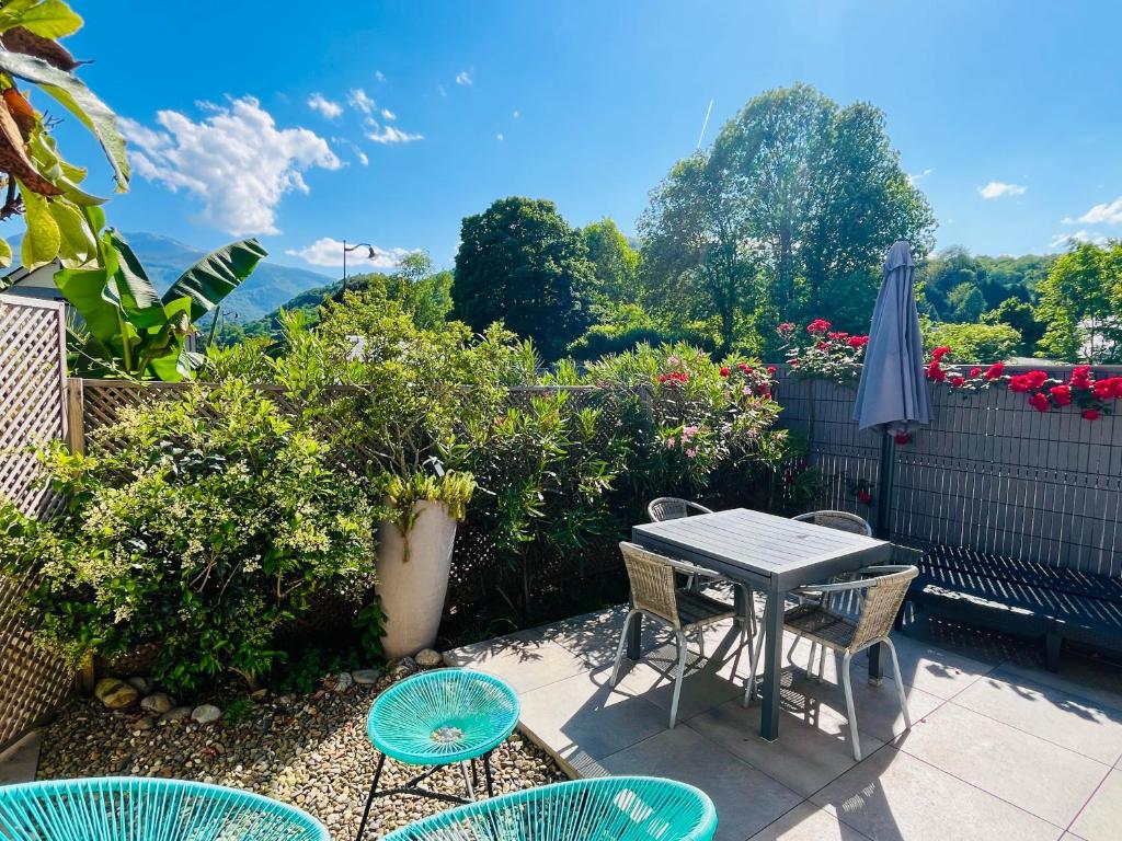 un patio avec une table, des chaises et un parasol dans l'établissement La maison de Lilette proche Argelès Gazost, à Ayzac-Ost