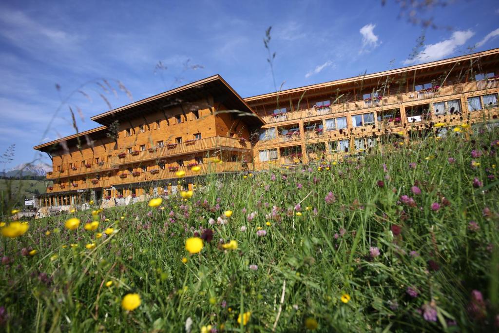 ein Gebäude mit einem Blumenfeld davor in der Unterkunft Sporthotel Floralpina in Alpe di Siusi