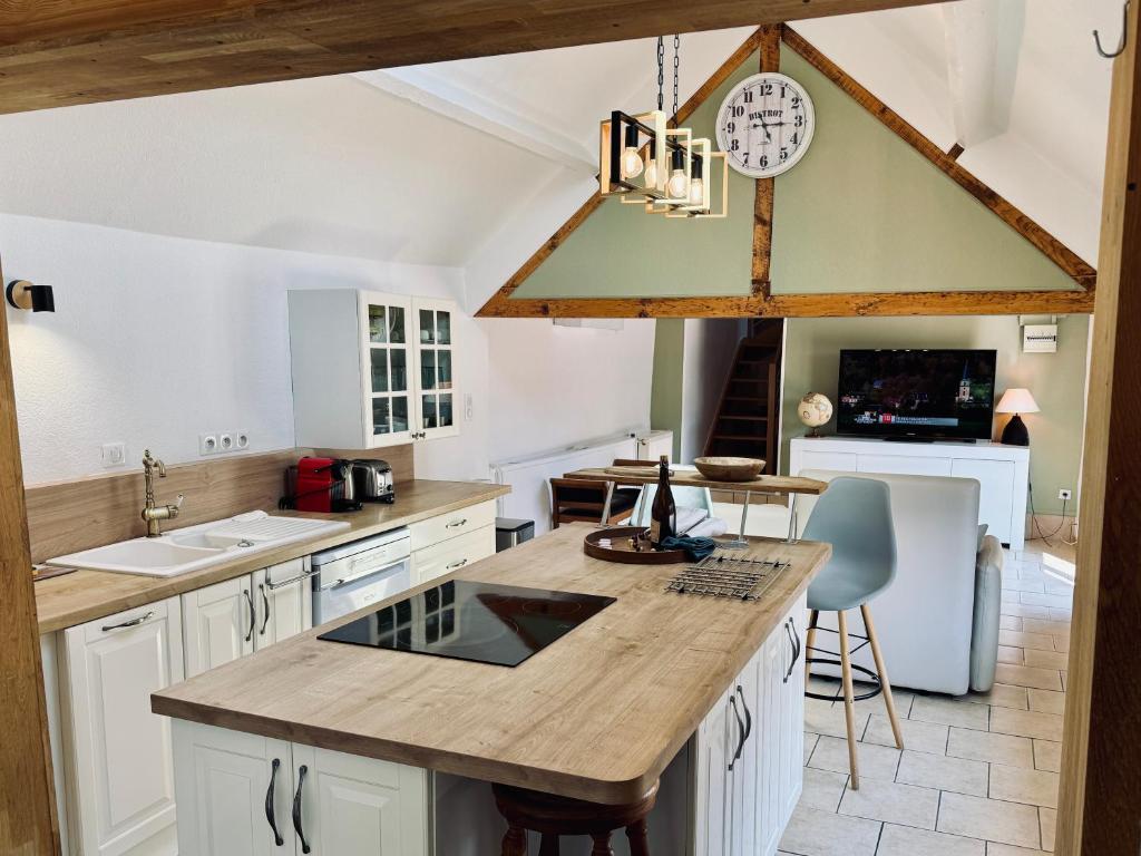 une cuisine avec des placards blancs et une horloge au plafond dans l'établissement « Au Fil du Bec », au Bec-Hellouin