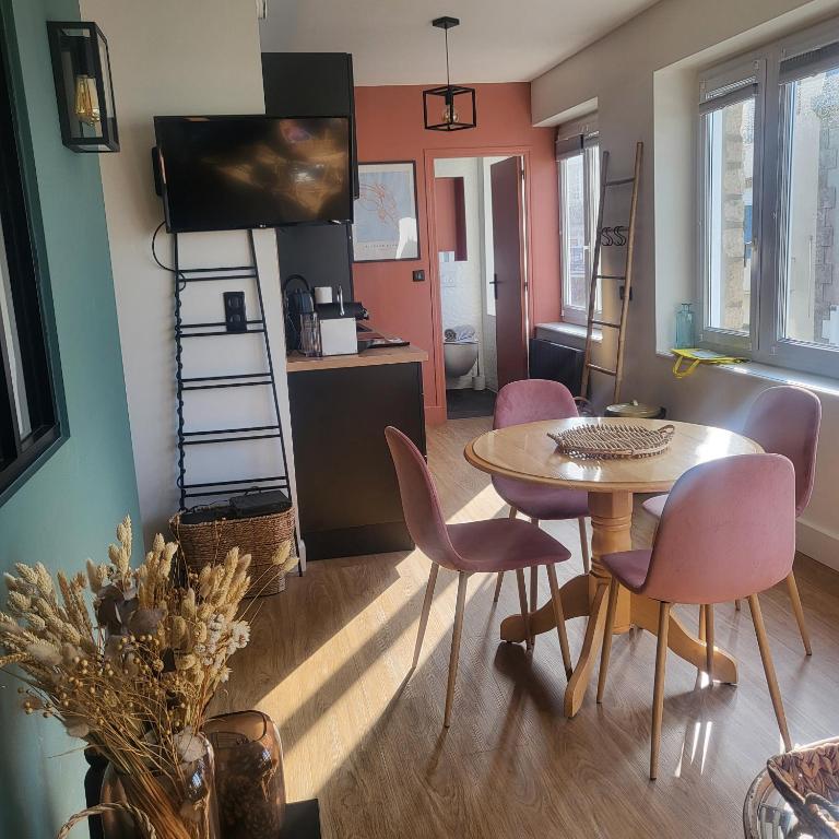 - un salon avec une table, des chaises et une télévision dans l'établissement Le Paille en Queue, à Fouesnant