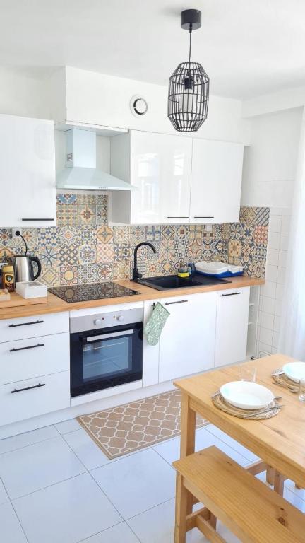 une cuisine avec des armoires blanches et une table en bois dans l'établissement Charmant logement entre la gare et le centre-ville, à Lorient