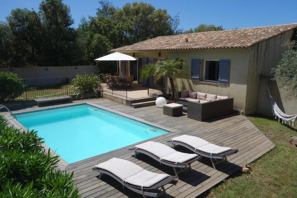 une piscine avec des chaises longues à côté d'une maison dans l'établissement Villa Morticcione, à Zonza