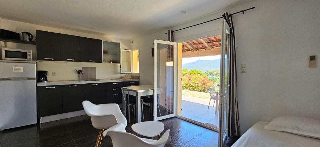 une cuisine avec des chaises blanches et une cuisine avec un balcon dans l'établissement Studio Dolce & Vita B2 avec piscine et terrasse, à Propriano