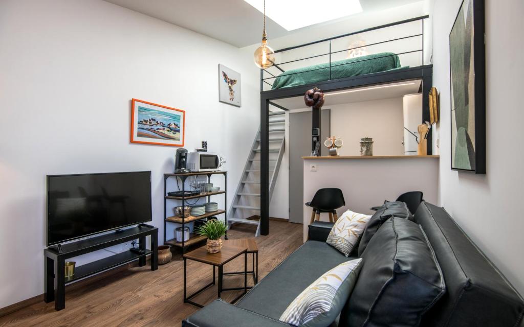 un salon avec un canapé noir et une télévision dans l'établissement Le minimaliste pk fibre clim terrasse, à Millau