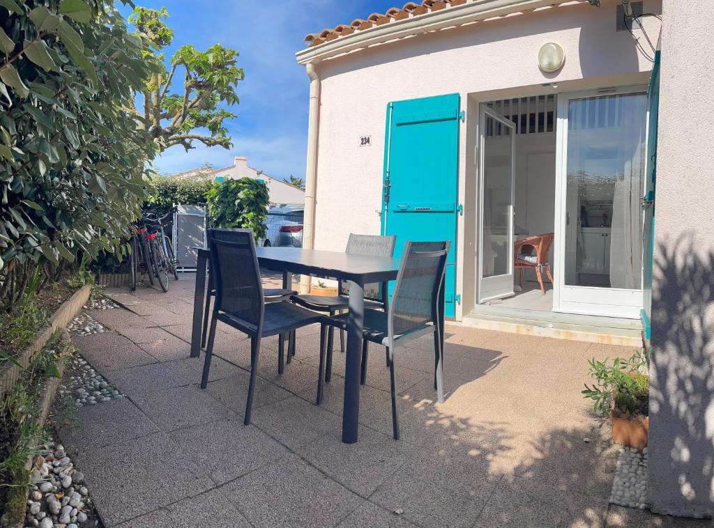 une table et des chaises assises sur une terrasse dans l'établissement Maison cosy près de la plage, à Bretignolles-sur-Mer